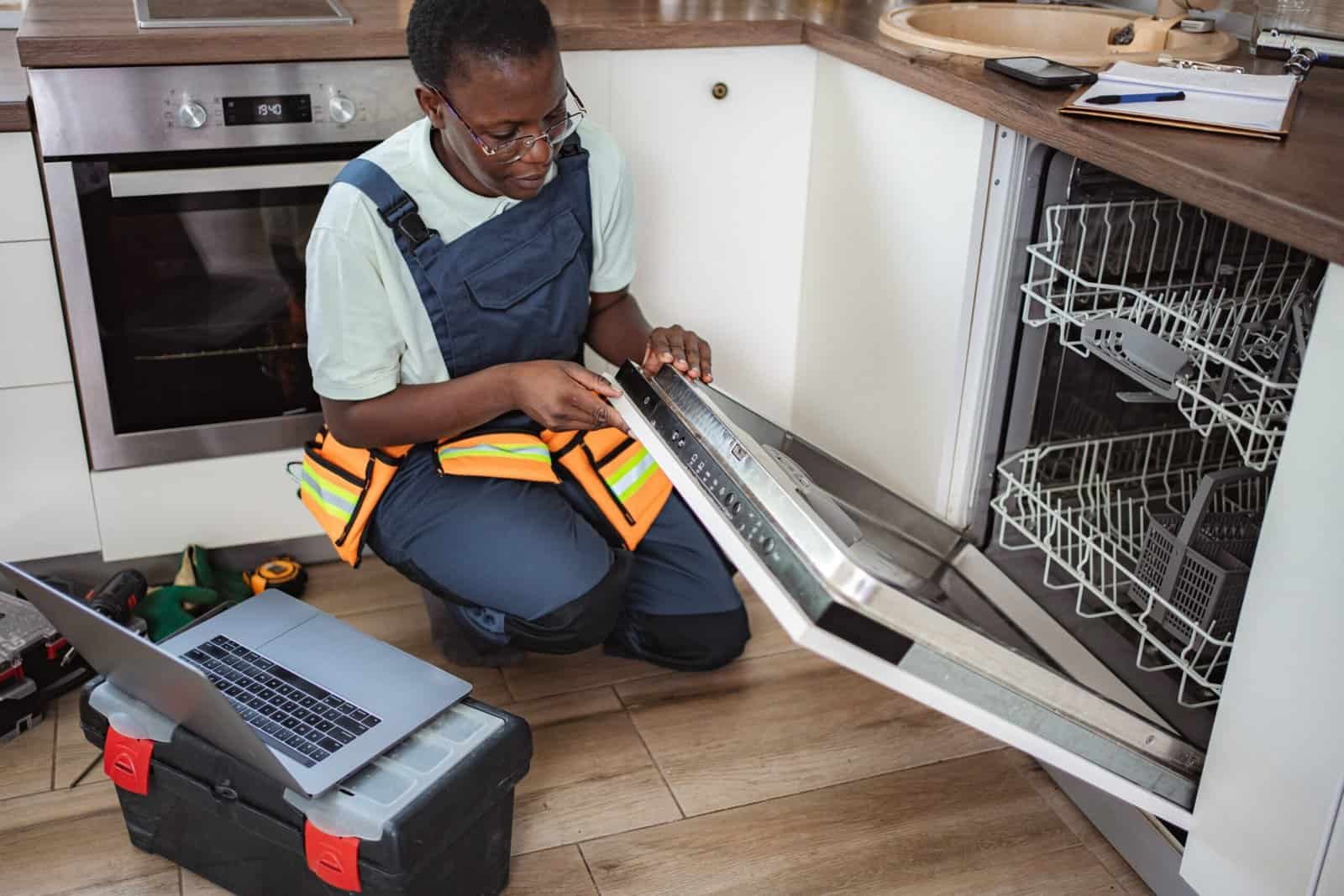 Technician inspecting dishwasher for maintenance or repair.