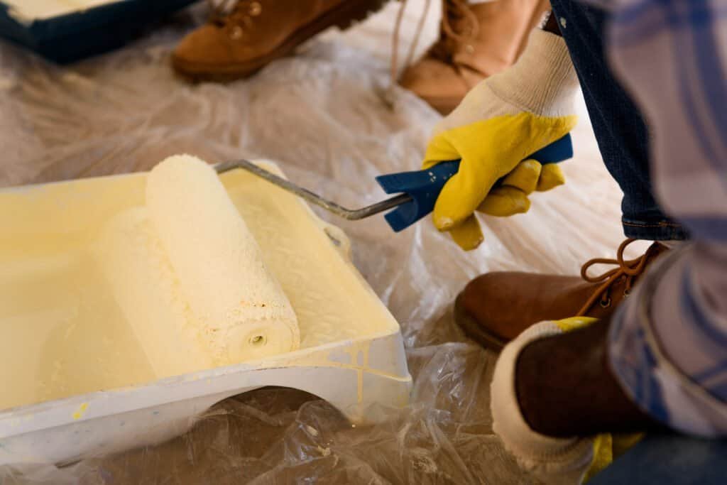 Professional painter applying yellow paint with a roller brush.